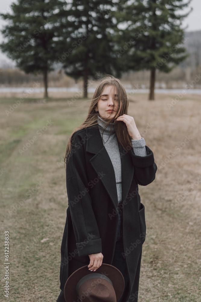 Young woman wearing long coat standing on field Young woman wearing long coat standing on field