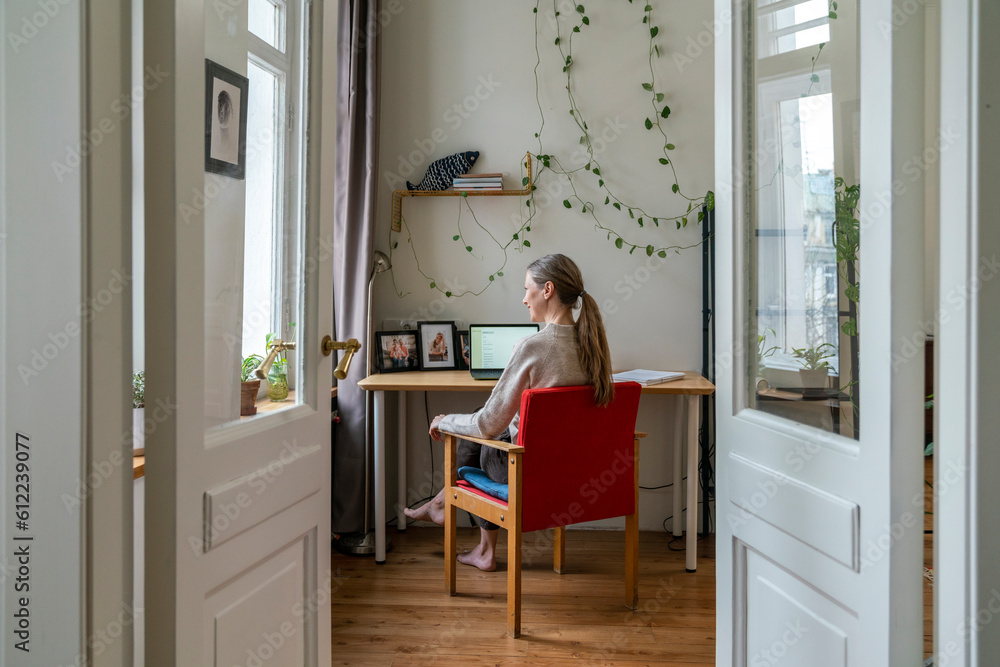 Contemplative freelancer sitting on chair at desk Contemplative freelancer sitting on chair at desk