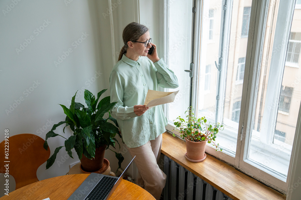 Freelancer with financial bills talking on smart phone Freelancer with financial bills talking on smart phone