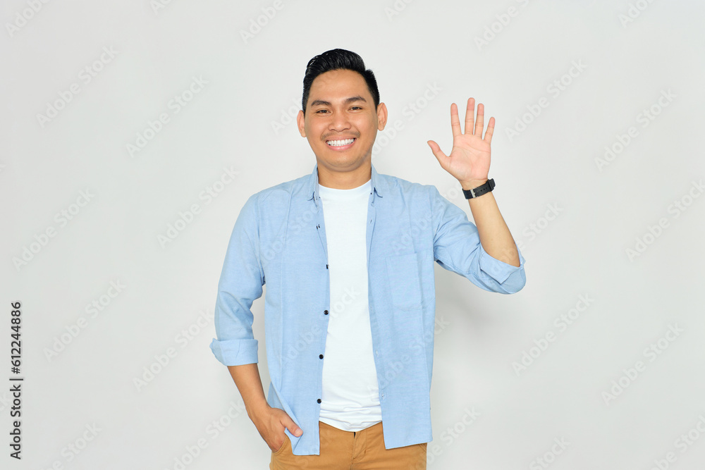 Hello. Portrait of friendly young Asian man in casual clothes showing hi gesture with waving hand and smiling isolated on white background Hello. Portrait of friendly young Asian man in casual clothes showing hi gesture with waving hand and smiling isolated on white background
