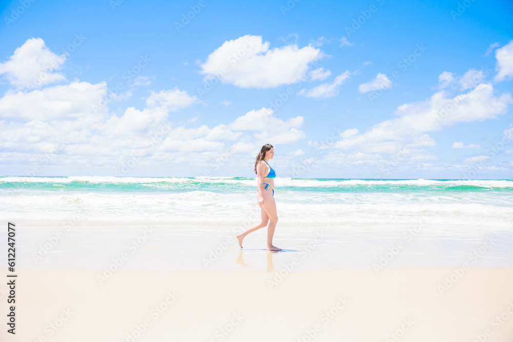 青い空と海の前を歩くビキニの白人女性