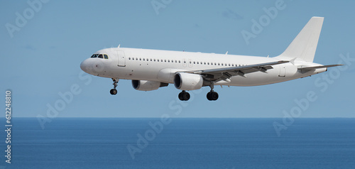 Airplane landing above ocean. Passenger aircraft. Business commercial. Landing to airport next to the beach. Airplane flies extremely low over the sea beach