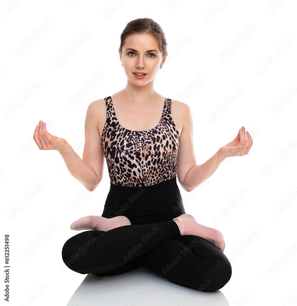 Full-length portrait of athletic woman in sports wear meditation in lotus position on the floor isolated on white background. Young woman in fitness clothes posing on the camera. Full-length portrait of athletic woman in sports wear meditation in lotus position on the floor isolated on white background. Young woman in fitness clothes posing on the camera.