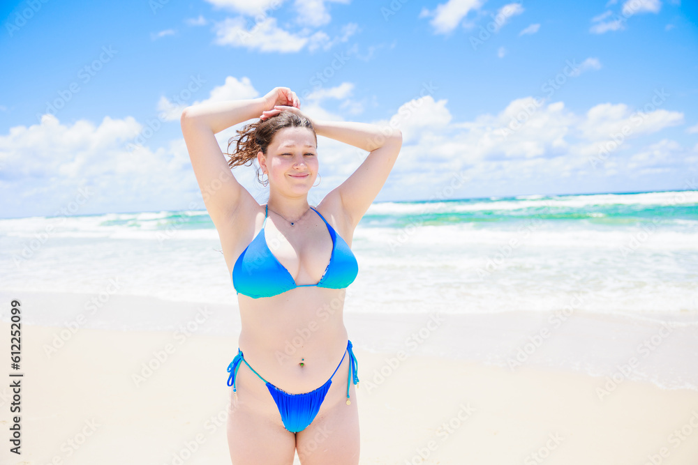 髪の毛を束ねる水着姿の白人女性