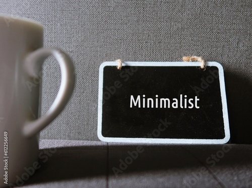 Photography Small chalkboard on gray wallpaper with text MINIMALIST , concept of living with