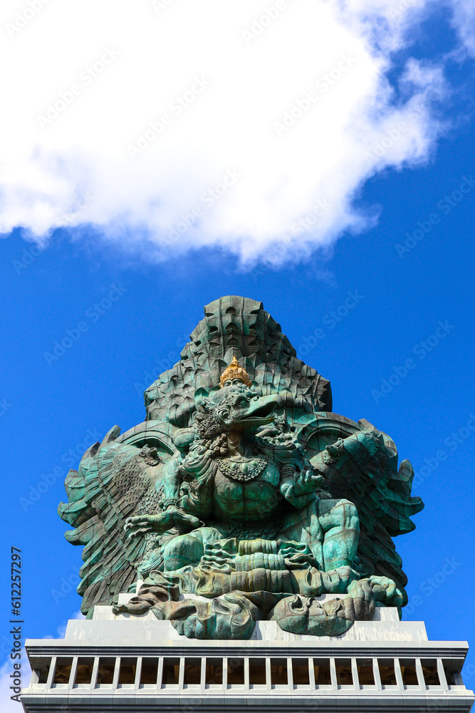 A portrait of Garuda Wisnu Kencana statue, an iconic cultural landmark in Bali, at the GWK Cultural Park with blue sky as background