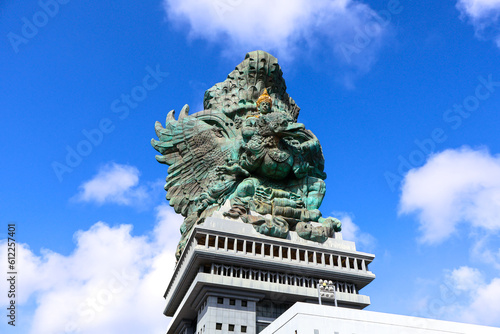 A portrait of Garuda Wisnu Kencana statue, an iconic cultural landmark in Bali, at the GWK Cultural Park with blue sky as background photo