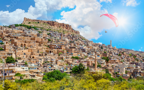 Paraglider flies in the sky - Mardin old town with bright blue sky - Mardin, Turkey