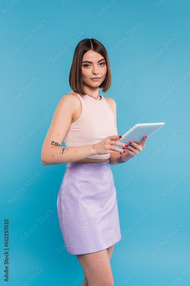 brunette young woman with short hair, tattoos and nose piercing digital tablet laptop on blue background, generation z, summer trends, attractive, social media influencers, tablet user brunette young woman with short hair, tattoos and nose piercing digital tablet laptop on blue background, generation z, summer trends, attractive, social media influencers, tablet user