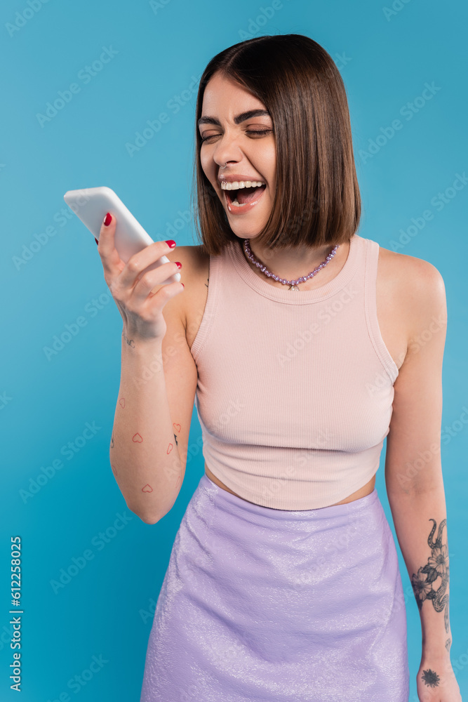 sending a message, excited young woman short hair, tattoos and nose piercing using mobile phone on blue background, casual attire, gen z fashion, social media influencers sending a message, excited young woman short hair, tattoos and nose piercing using mobile phone on blue background, casual attire, gen z fashion, social media influencers