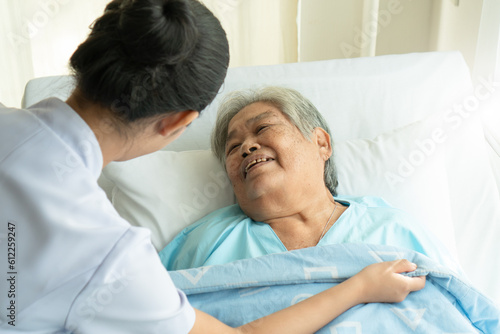Nursing care home concept. Caretaker helping grandma on the bed.