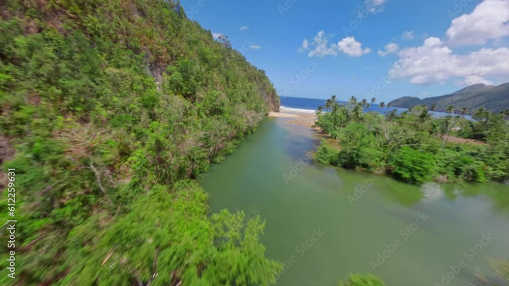 FPV flight over idyllic Rio San Juan flowing into Caribbean Sea with sandy beach and green coastline - El Valle, Samana, Dominican Republic FPV flight over idyllic Rio San Juan flowing into Caribbean Sea with sandy beach and green coastline - El Valle, Samana, Dominican Republic