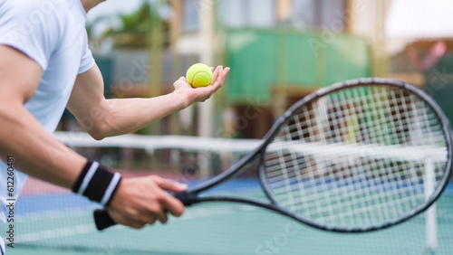Cropped shot of male tennis player with racket and ball preparing to serve at beginning of game or match. © wattana
