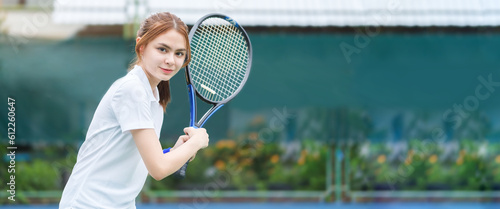 Focused sportswoman in white costume playing tennis on outdoor court at evening. Movement, sport, healthy lifestyle concept.