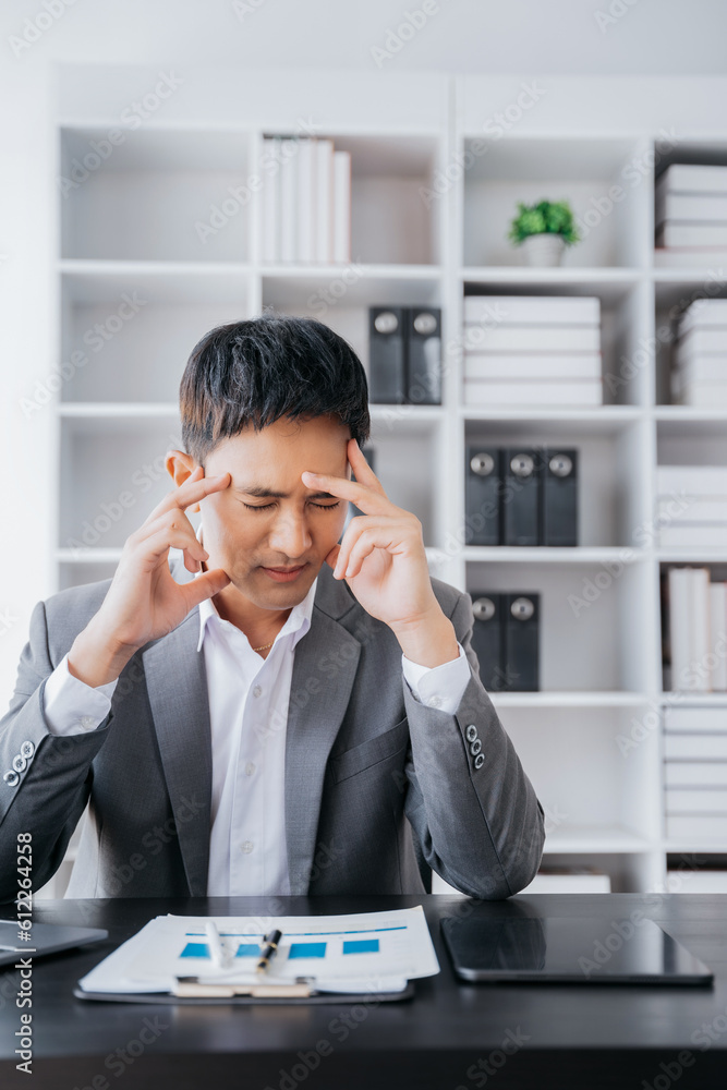 Young stressed Asian businessman working in the office. Businessman thinking too much work concept in the office. Young stressed Asian businessman working in the office. Businessman thinking too much work concept in the office.