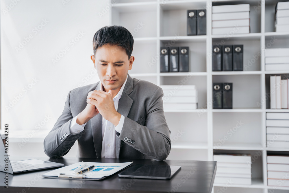 Young stressed Asian businessman working in the office. Businessman thinking too much work concept in the office. Young stressed Asian businessman working in the office. Businessman thinking too much work concept in the office.
