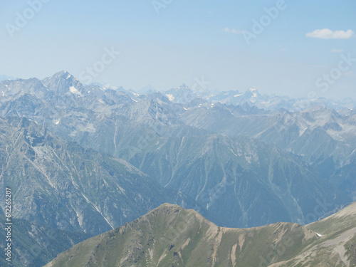 Aerial panoramic view of the Main Caucasus Mountain Ridge from Mount Elbrus, the highest summit in Europe, glacier Seven, incredible blue sky background, impressive nature landscape in North Caucasus