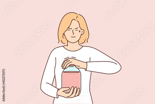 Casual weak woman opens jar of juice or compote, trying to unscrew tight jammed lid