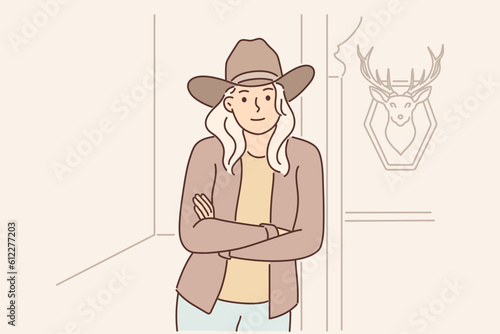 Woman ranger and ranch owner stands with arms crossed near wall with stuffed deer