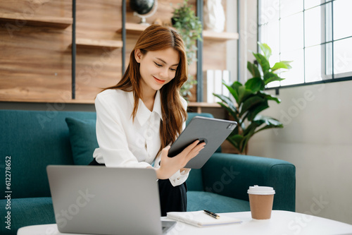 Business woman using tablet and laptop for doing math finance  tax  report  accounting  statistics  and analytical research concept on sofa in home office.