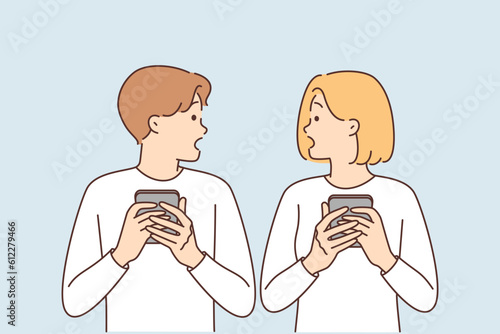 Shocked couple with phones surprised to read news or receive SMS mailing about bad weather