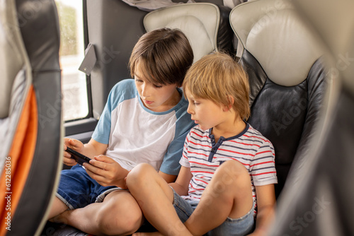Wall Mural Children, siblings, playing on a mobile phone while traveling with bus on a long