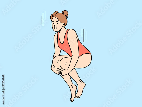 Woman swimmer jumps from springboard to dive underwater into pool or sea. Girl in swimsuit dives into pool while participating in ski jumping or synchronized swimming competitions.
