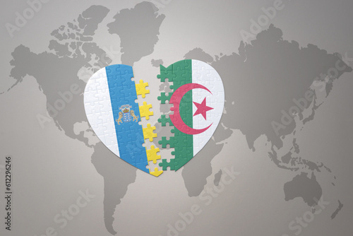 puzzle heart with the national flag of algeria and canary islands on a world map background.Concept.