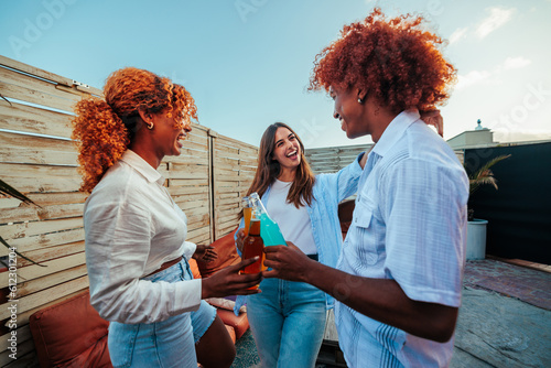 Three multiracial young people celebrating and toasting on rooftop