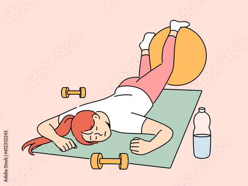 Exhausted woman in fitness room fell asleep on sports yoga mat and needs to rest after workout. Lazy girl sleeps in fitness club, not wanting to do athletics and listen to advice of personal trainer
