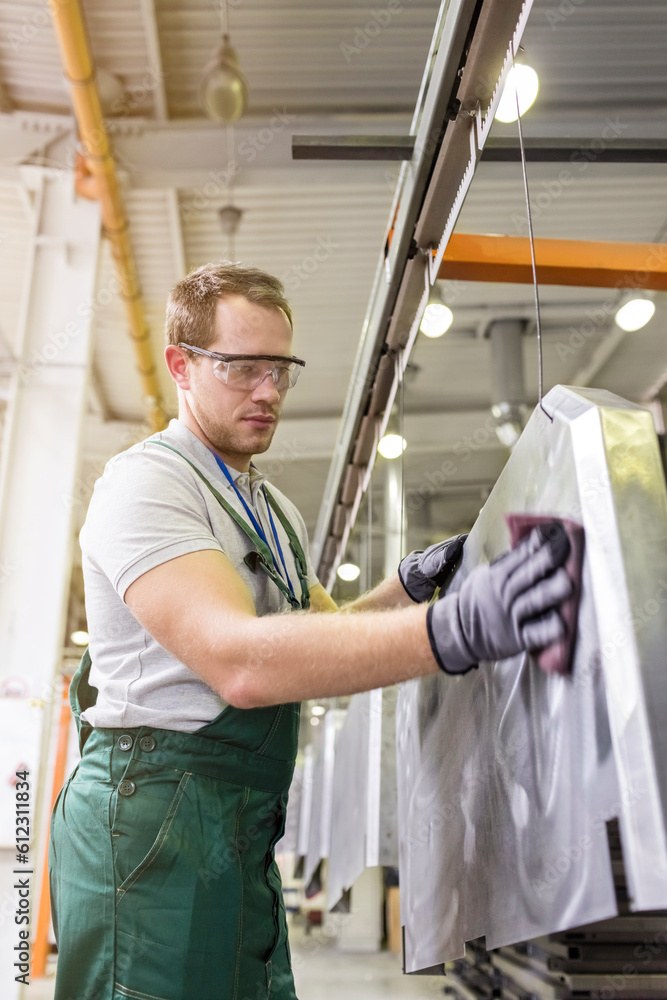 Worker sanding steel part in factory Worker sanding steel part in factory