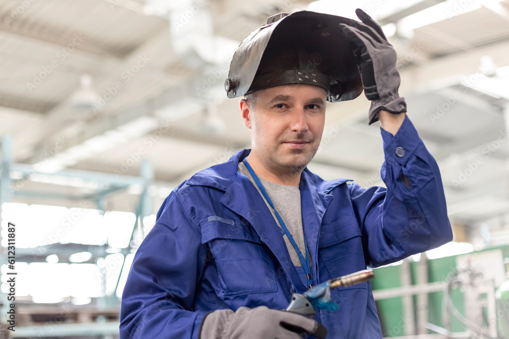 Portrait confident welder with welding torch in factory Portrait confident welder with welding torch in factory