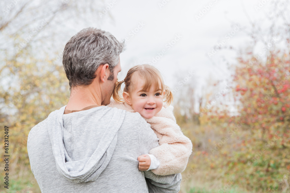 Father holding smiling toddler girl in park Father holding smiling toddler girl in park
