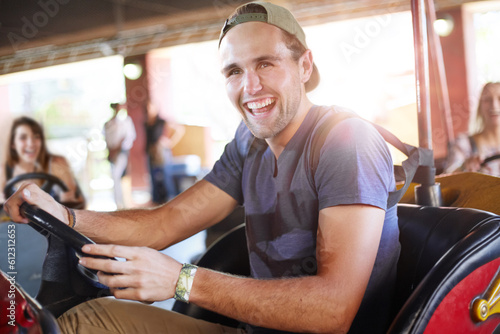 Laughing young man riding bumper cars at amusement park photo