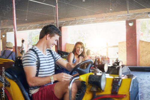 Young couple riding bumper cars at amusement park photo