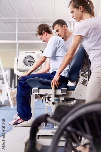 Physical therapists guiding man using equipment