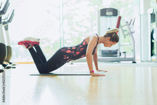 Woman doing push-ups on knees at gym photo