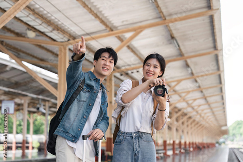 Beautiful couple at railway station waiting for the train. Young woman take pictures of trains. woman and man waiting to board a train
