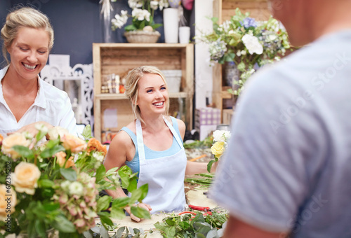 Florists arranging bouquet and talking to customer in flower shop