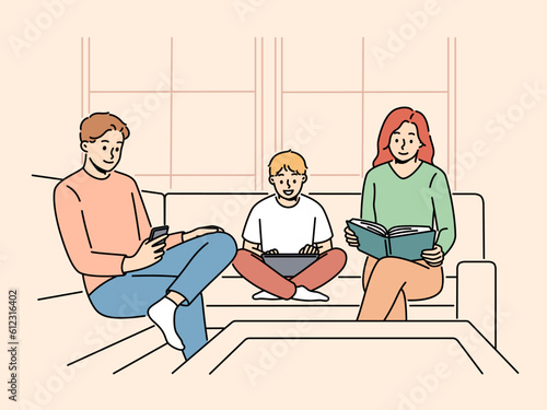 Family is sitting on couch ignoring each other for concept of communication problems. Mom and dad with their son are passionate about different things and need communication for family happiness