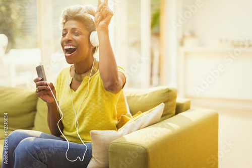 Playful mature woman listening to headphones MP3 player in living room photo