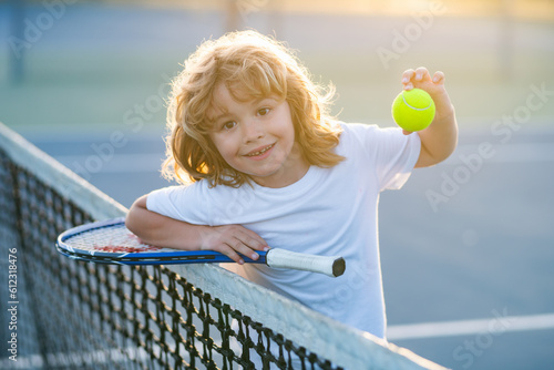 Child with tennis racket and tennis ball playing on tennis court. © Volodymyr