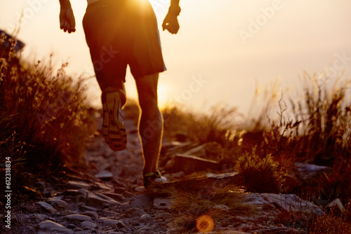 Man running on craggy trail at sunset
