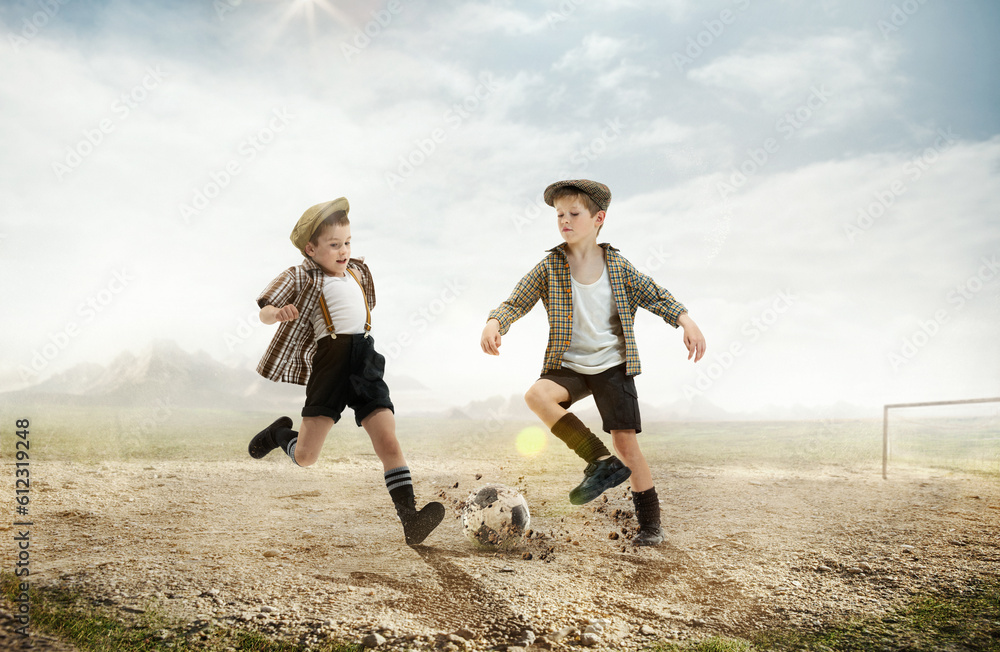 Active little boys, children in retro style clothes playing football outdoors on a daytime. warm sunny day on countryside Active little boys, children in retro style clothes playing football outdoors on a daytime. warm sunny day on countryside