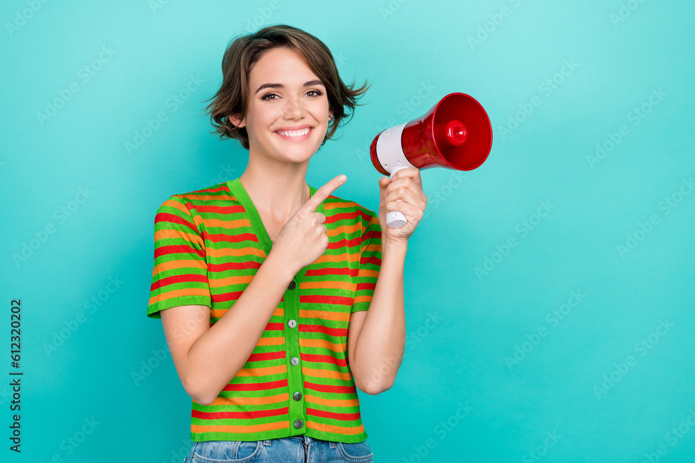 Photo of pretty sweet lady wear striped cardigan pointing finger loud speaker empty space isolated teal color background Photo of pretty sweet lady wear striped cardigan pointing finger loud speaker empty space isolated teal color background