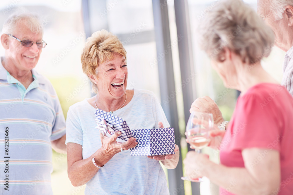 Senior woman opening birthday gift with friends Senior woman opening birthday gift with friends