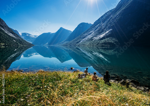 Friends relaxing at sunny tranquil mountain lakeside, Norway
