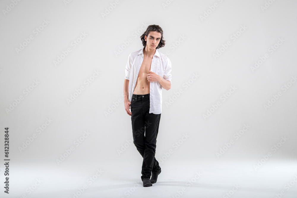 Full-length portrait of a standing handsome young man model in a white shirt and jeans on a white background. Full-length portrait of a standing handsome young man model in a white shirt and jeans on a white background.