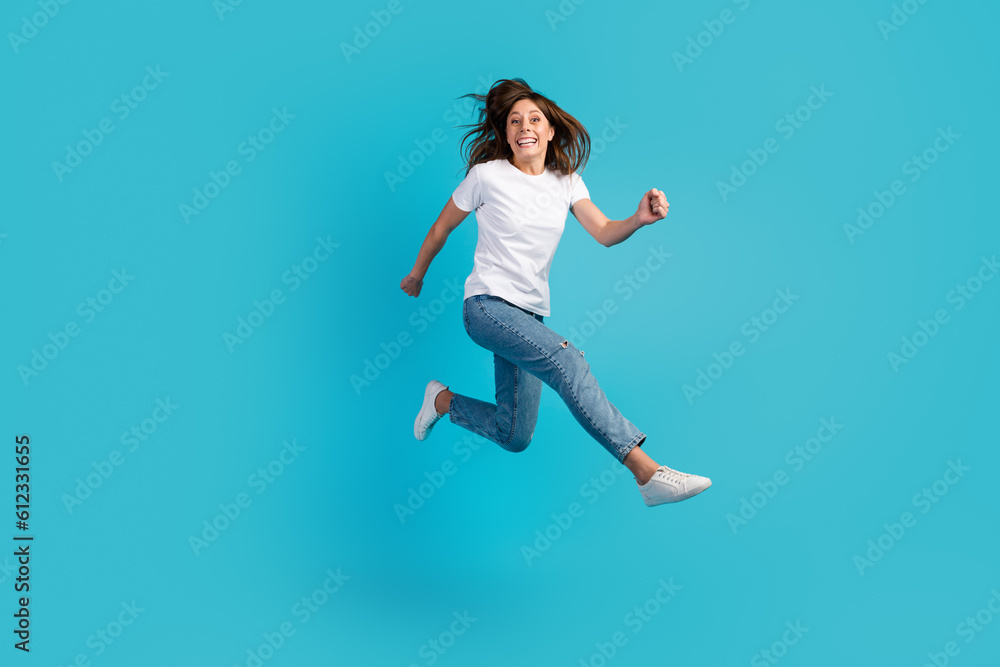 Photo of pretty charming woman dressed white outfit jumping high running fast empty space isolated blue color background
