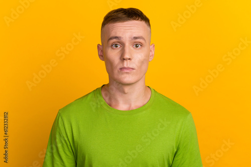 Isolated shot of young handsome male with trendy hairdo, wears casual sweater has serious expression poses in studio against yellow background